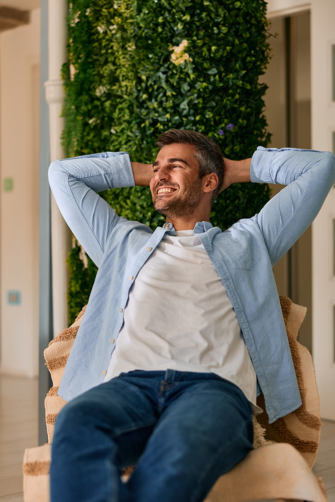 happy man relaxing at home with green plant wall